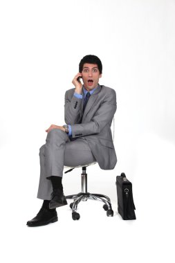 Portrait of businessman sitting on swivel chair looking amazed clipart