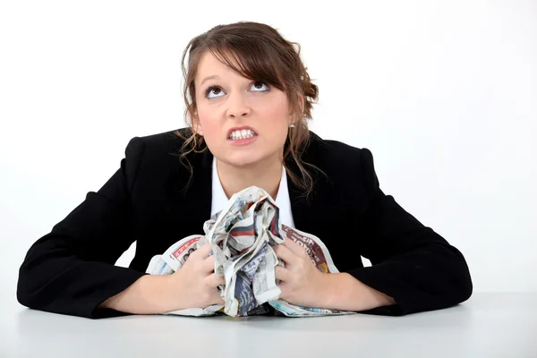 Angry businesswoman crushing a newspaper — Stock Photo, Image