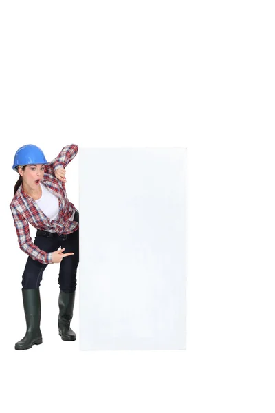 Tradeswoman pointing to a blank sign — Stock Photo, Image