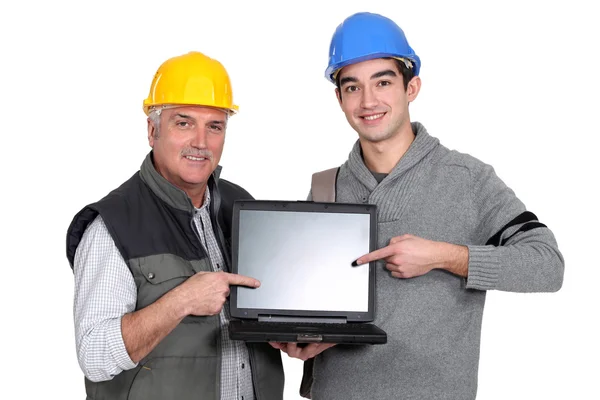 Budowniczy i pracowników młodzieżowych, wskazując na laptopa — Zdjęcie stockowe