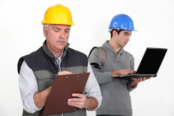 Bauarbeiter stand mit jungem Lehrling — Stockfoto