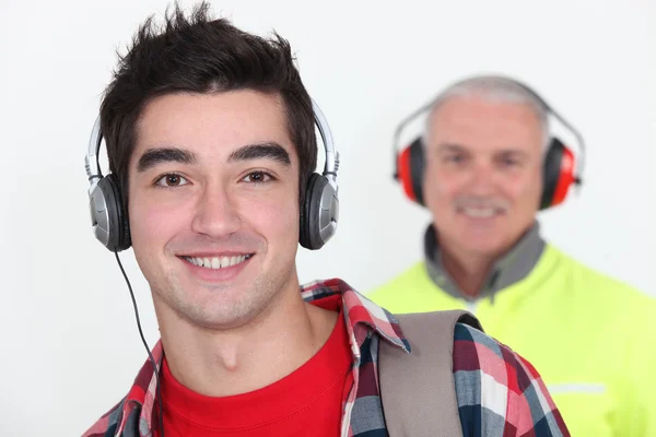 Student sobie słuchawki z przodu pracownik sobie nauszniki — Zdjęcie stockowe