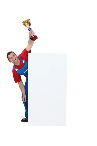 Trabalhador manual ficou por cartaz em branco enquanto segurava o troféu — Fotografia de Stock