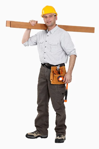 Um carpinteiro carregando pranchas . — Fotografia de Stock