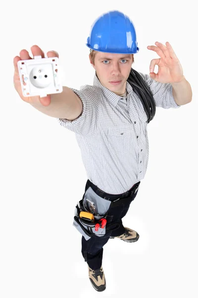 Elektriker hält eine Steckdose und macht ein Okay-Zeichen — Stockfoto