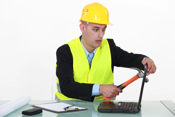 Construtor esmagando a tela do laptop com martelo — Fotografia de Stock