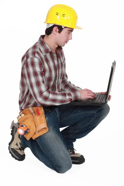 Laborer kneeling with computer — Stock Photo, Image