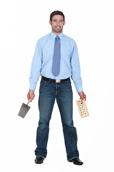 Podnikatel drží lopatu a cihla — Stock fotografie