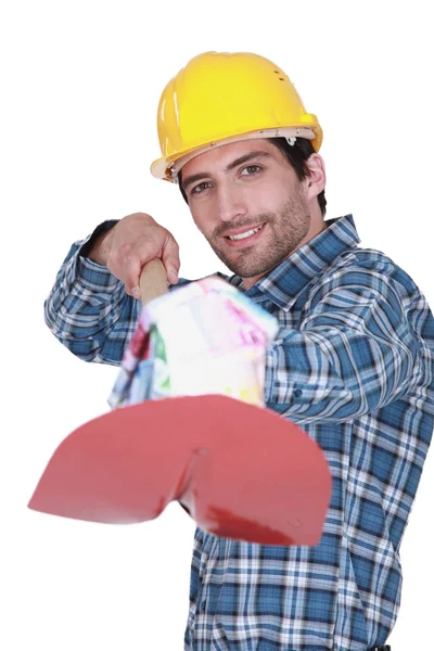 Man holding a small house with a shovel — Stock Photo, Image