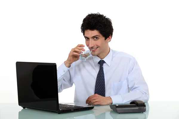 남자 마시는 물의 유리 책상에 앉아 — 스톡 사진
