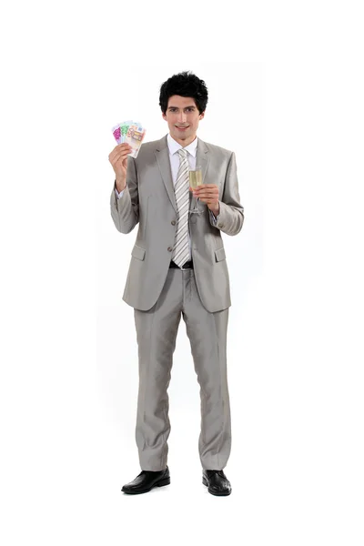 Businessman holding money in cash and a glass of champagne — Stock Photo, Image