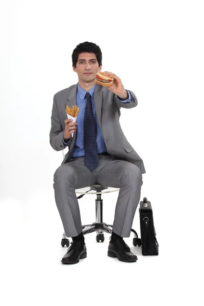Obchodník seděl jíst hamburger a hranolky — Stock fotografie