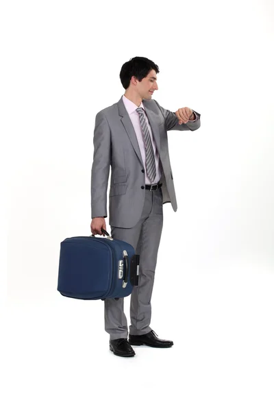 Empresário com bagagem consultando seu relógio — Fotografia de Stock