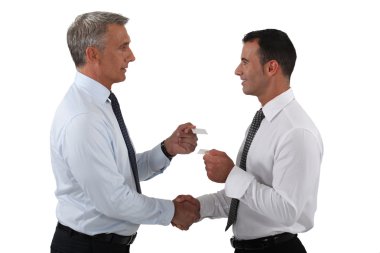 Businessmen shaking hands and exchanging cards clipart