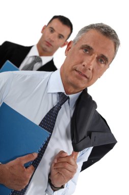 Portrait of a businessman with his assistant trailing behind him clipart