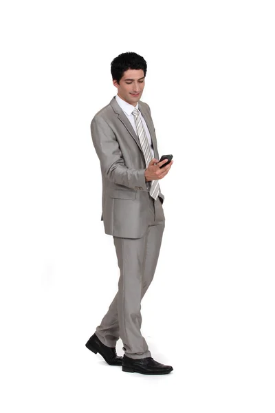 Jovem empresário enviando mensagem de texto enquanto caminha — Fotografia de Stock