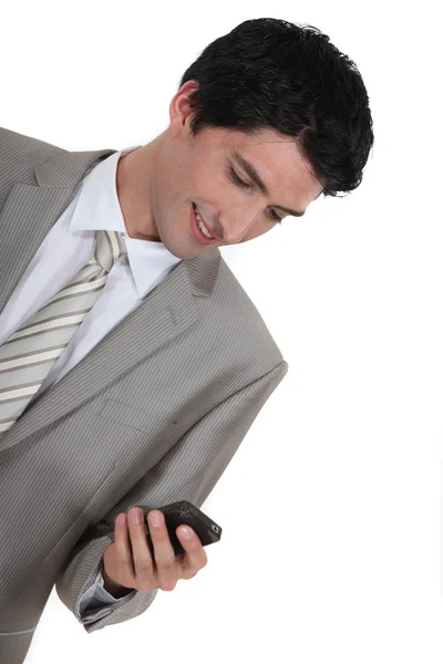 Smiling businessman reading message on the phone — Stock Photo, Image
