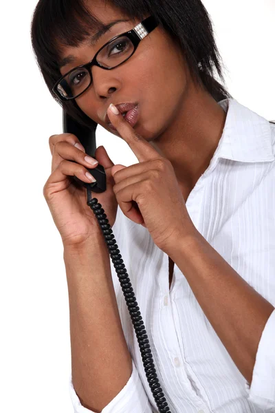 Mulher ao telefone fazendo um sinal de silêncio — Fotografia de Stock