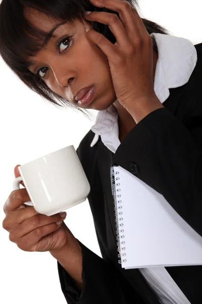 Uma mulher de negócios afro-americana ao telefone a beber um café . — Fotografia de Stock