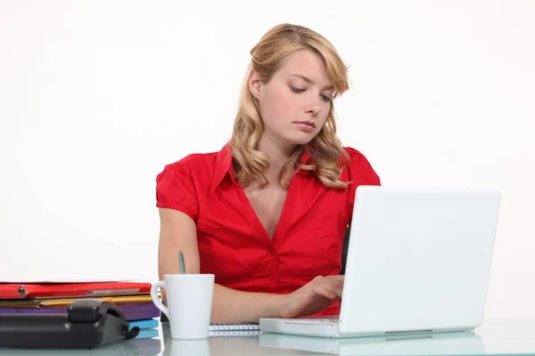Gelangweilte Sekretärin tippt auf ihrem Laptop — Stockfoto