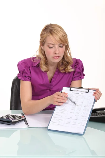 Blonde Büroangestellte zeigt mit Stift auf Klemmbrett — Stockfoto