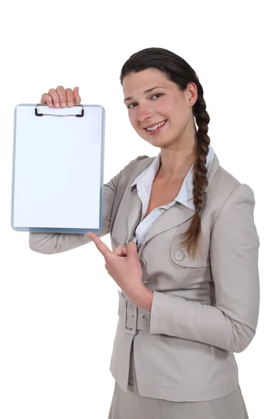 Mulher apontando para clip-board em branco — Fotografia de Stock