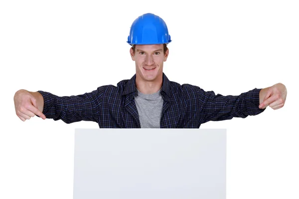Builder stood pointing at large billboard — Stock Photo, Image