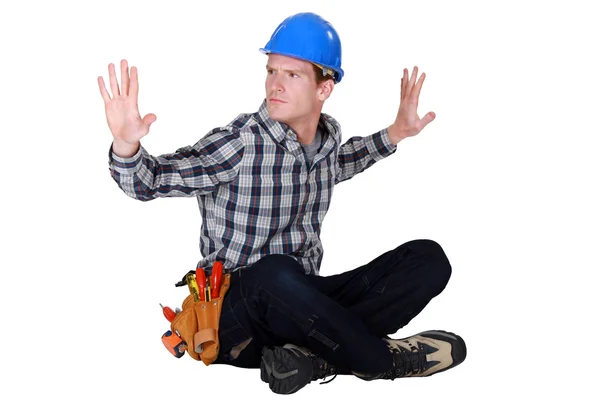 Handwerker sitzt im Schneidersitz auf dem Boden Hände hoch — Stockfoto