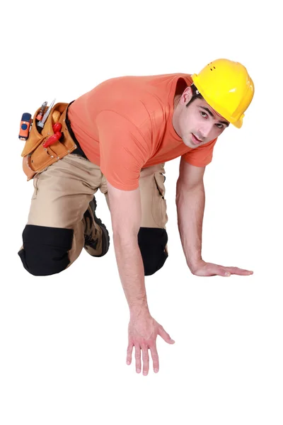 Kneeling tradesman reaching down — Stock Photo, Image