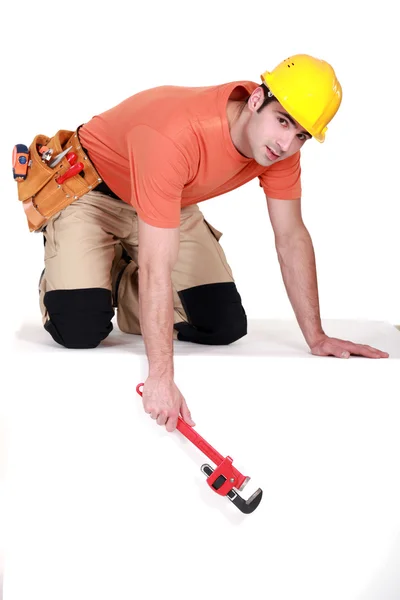 Tradesman que pendura uma chave de tubo de uma borda — Fotografia de Stock