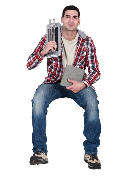 Uomo con tagliapiastrelle seduto sulla sporgenza — Foto Stock