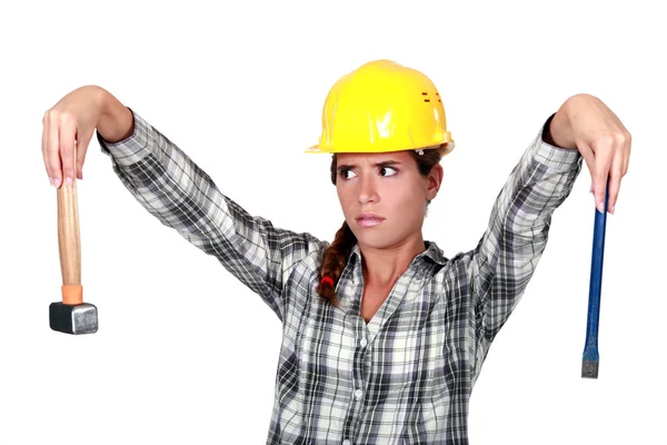 Apprehensive tradeswoman holding a hammer and chisel — Stock Photo, Image