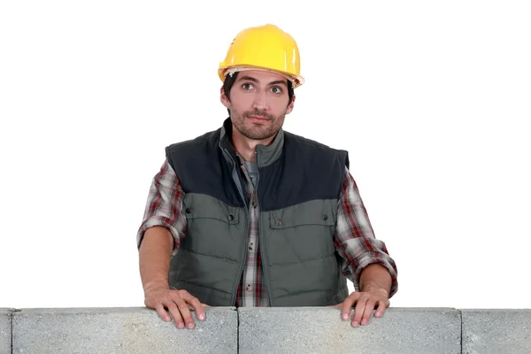 Handwerker lehnt an einer Steinblockmauer — Stockfoto