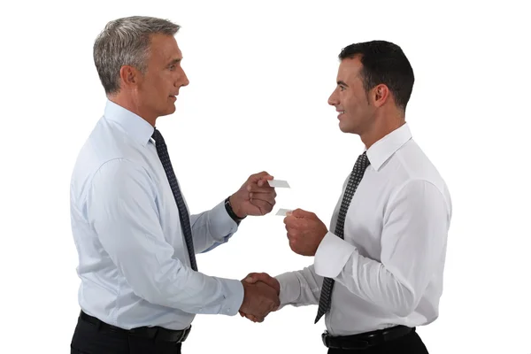Empresários apertando as mãos e trocando cartões — Fotografia de Stock