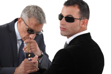 Businessmen wearing sunglasses and smoking a cigar clipart