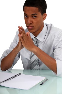 Uninspired young man sitting in front of an empty notebook clipart