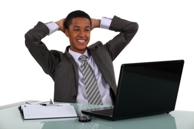 Relaxed businessmen smiling at his laptop clipart