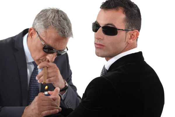 Hommes d'affaires portant des lunettes de soleil et fumant un cigare — Photo