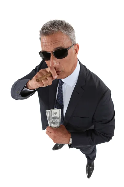 Um bandido segurando dinheiro roubado e fumando um charuto — Fotografia de Stock