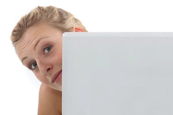 Frau blickt um einen Computer herum — Stockfoto