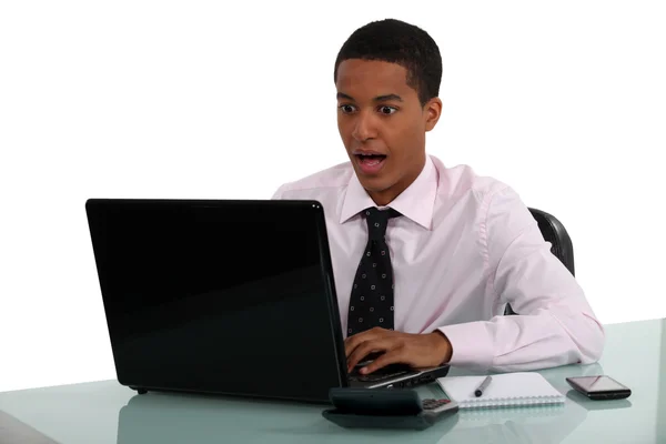 Młody człowiek przerażony na swoim komputerze — Zdjęcie stockowe