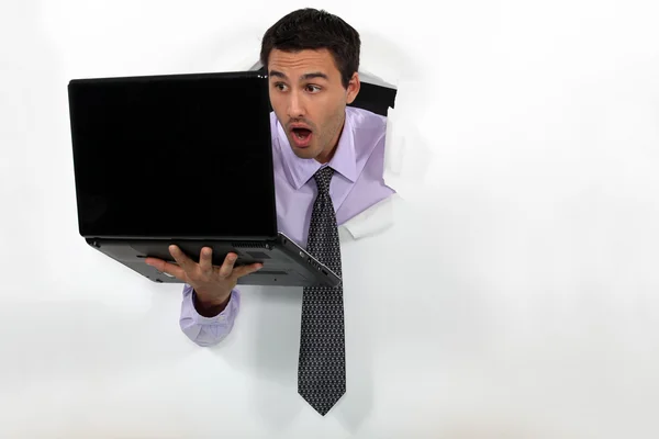 Человек с шокированным выражением лица держит ноутбук — стоковое фото