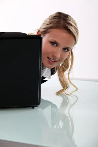 Junge Frau blickt um ihren Laptop herum — Stockfoto