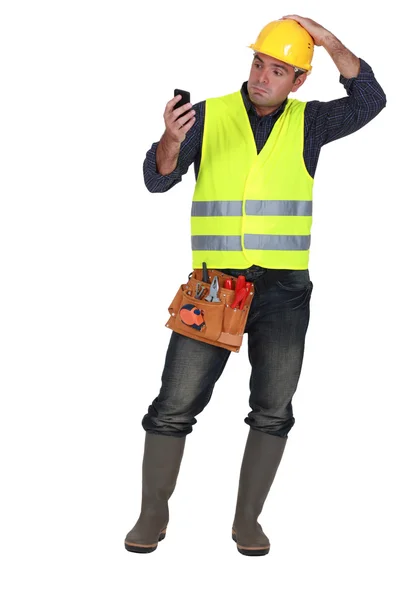Confused builder looking at mobile telephone — Stock Photo, Image