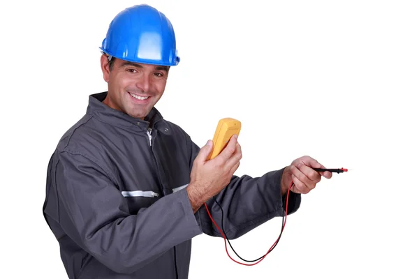 Eletricista segurando uma ferramenta de medição e sorrindo — Fotografia de Stock