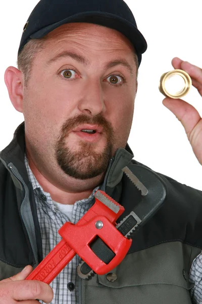 Ambachtsman holding een metalen stuk en een moersleutel — Stockfoto
