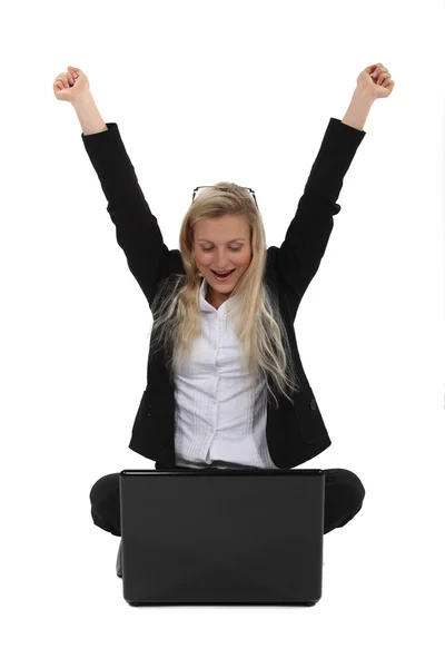Excited businesswoman sat on the floor with laptop Stock Picture