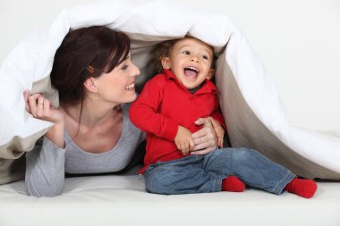 Woman playing a hiding game with her child clipart