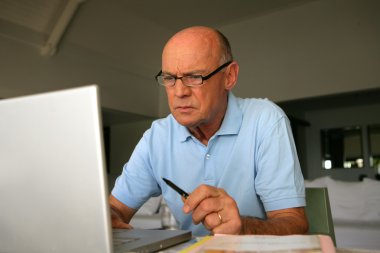 Elderly man concentrating on his work clipart