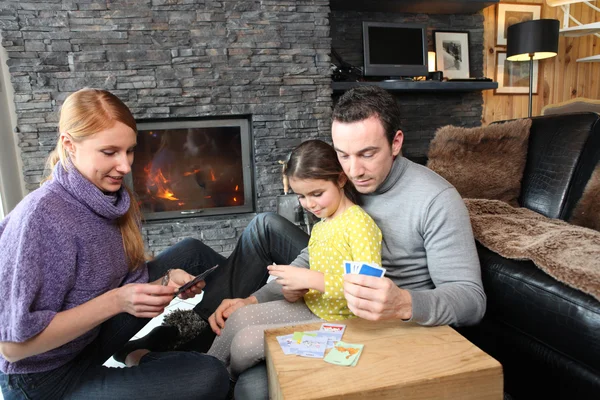 Famille rassemblée près de la cheminée jouant aux cartes — Photo